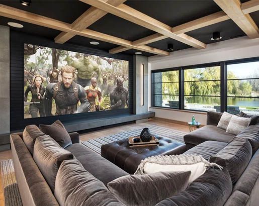 a living room with couches and a large screen on the wall