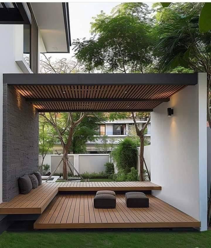 an outdoor living area with wooden flooring and benches on the side of the building