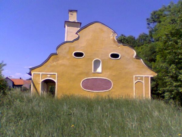 a house with a face painted on it's side in the middle of a field