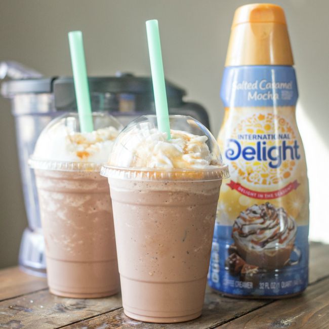 two drinks are sitting on a table next to a bottle of ice cream and a blender