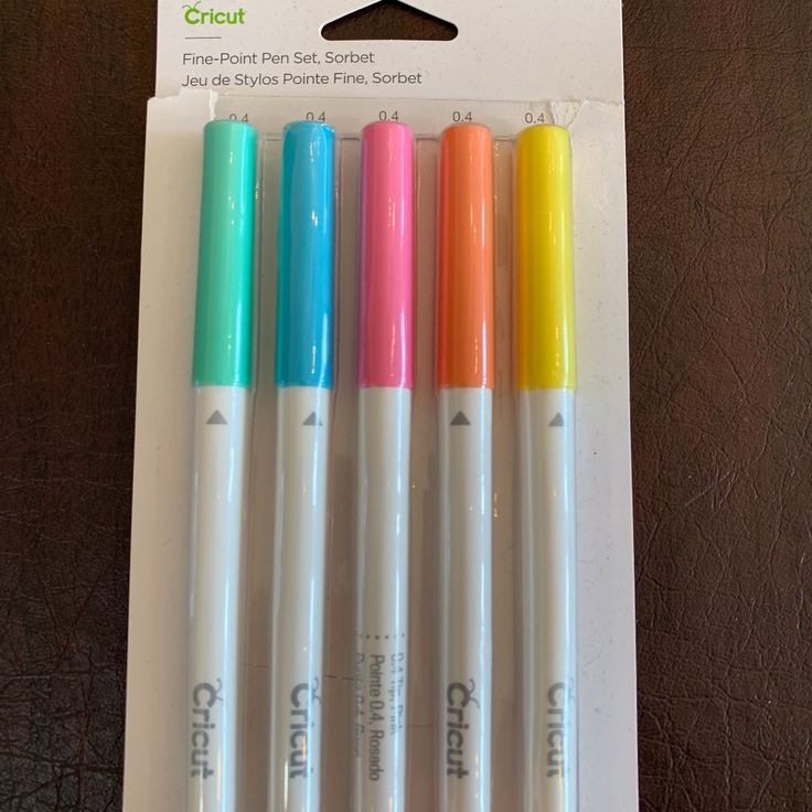 four different colored pens sitting on top of a table next to each other in a package