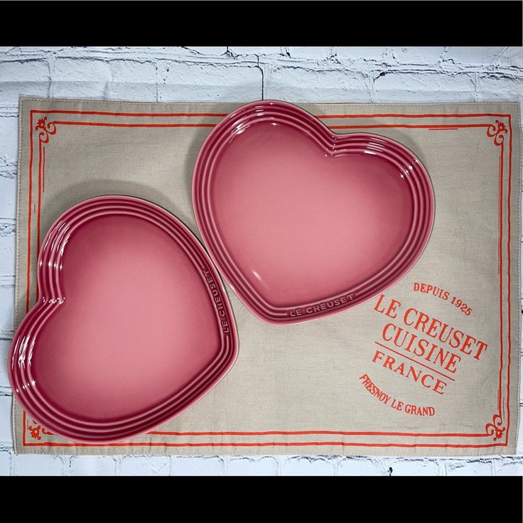 two pink heart shaped dishes sitting on top of a table