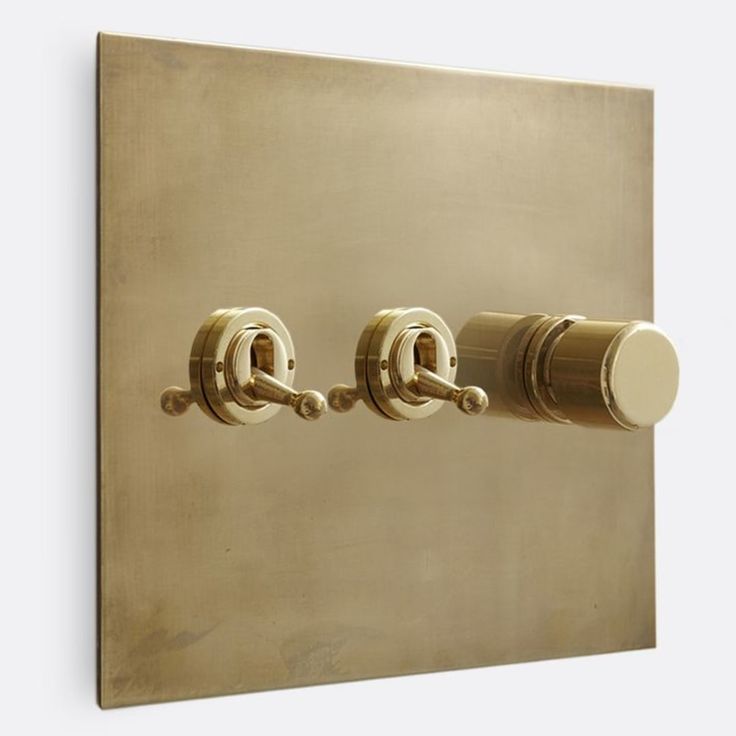 two knobs are attached to the side of a wall mounted light switch in an antique brass finish