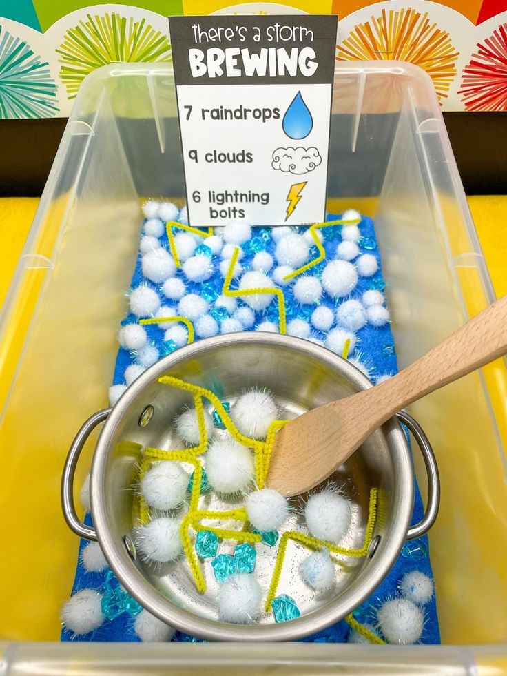 a container filled with lots of balls and a wooden spoon sitting on top of it