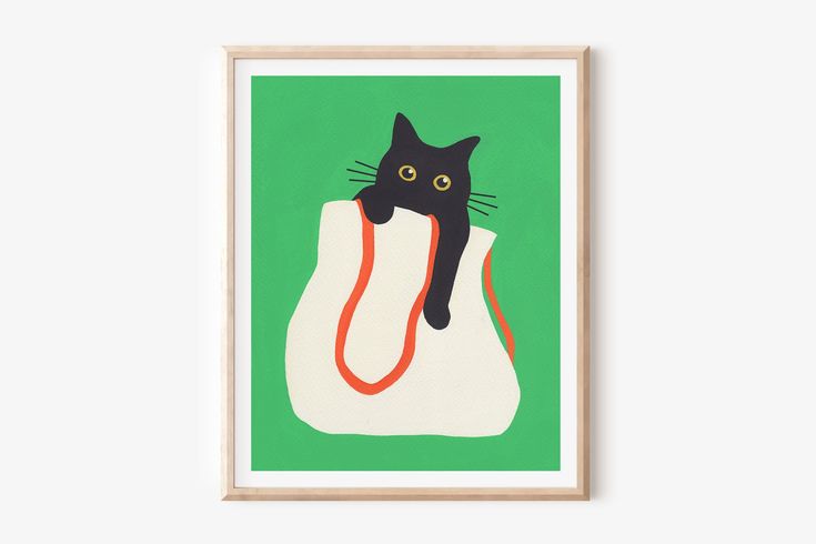 a black cat sitting in a white bag on a green background, framed art print