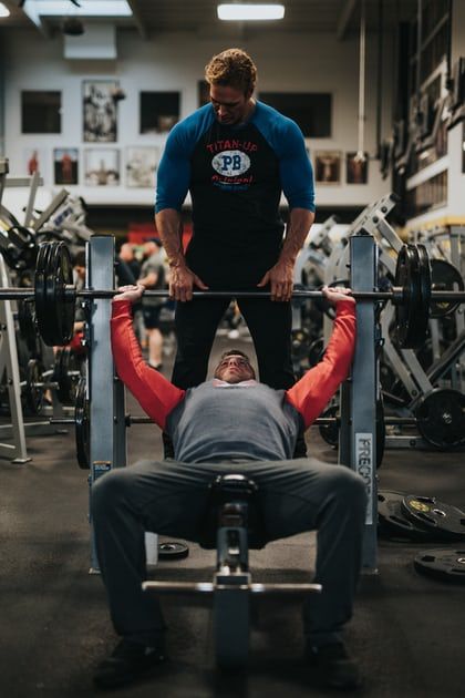 two men doing exercises in a gym with barbells