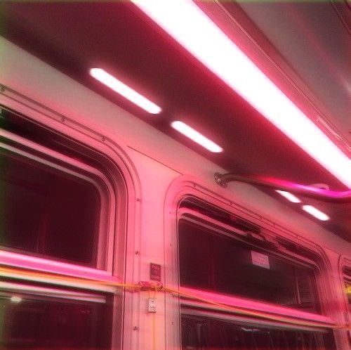 the inside of a subway car with red and pink lights on it's side