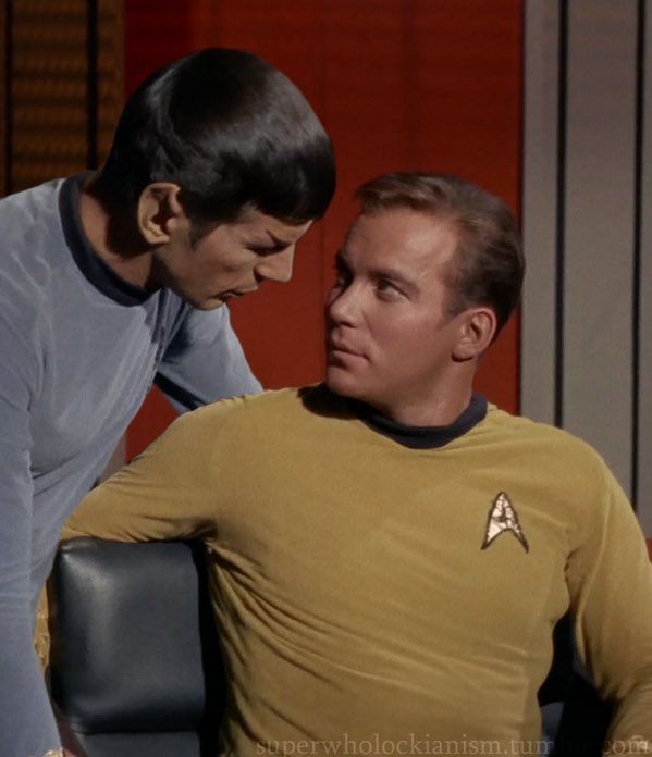 two men in star trek uniforms one is looking at the other man's face