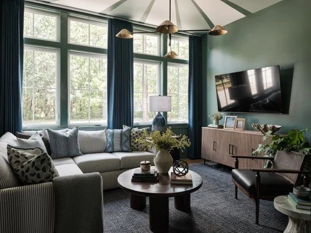 a living room filled with lots of furniture next to large windows and a flat screen tv mounted on the wall