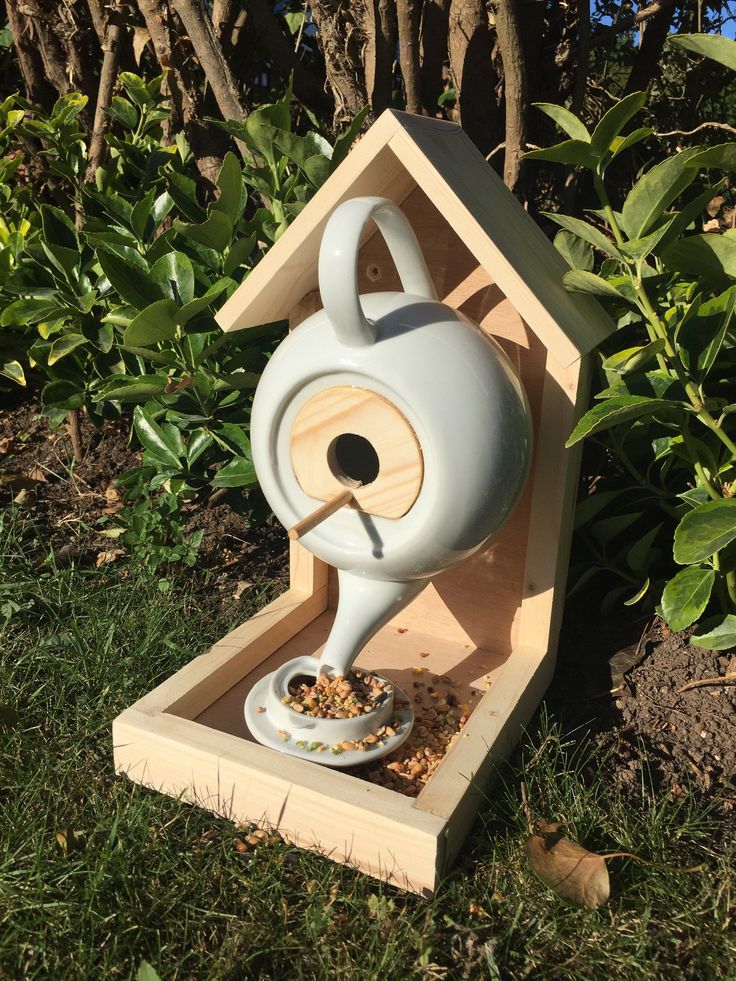 a bird feeder with a teapot shaped like a house