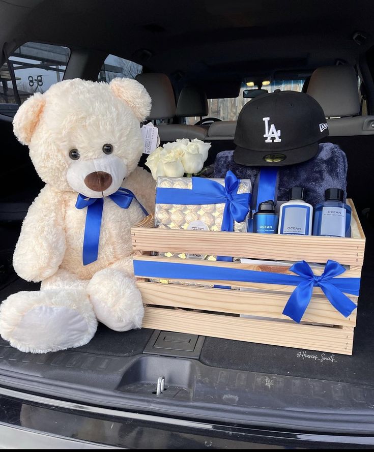 a white teddy bear sitting in the back of a car next to a wooden crate