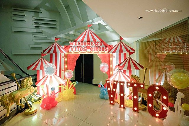 an entrance to a circus themed party with balloons and lights on the floor, in front of a sign that says welcome