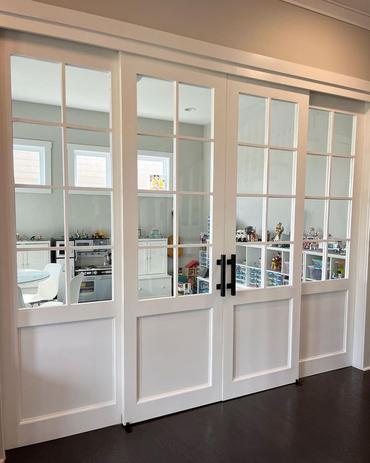 an empty room with white doors and black flooring is shown in front of the kitchen