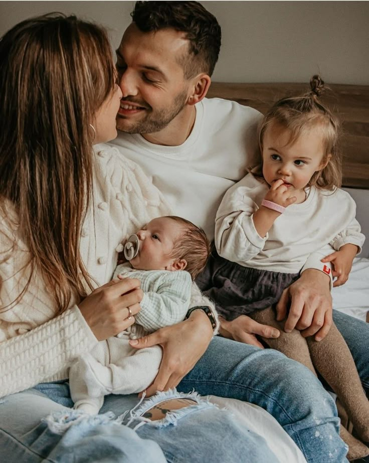 a man, woman and baby sitting on a bed with their hands around each other