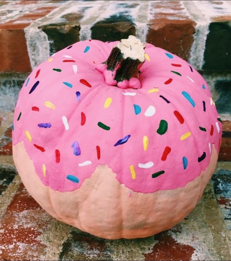 a pink donut with sprinkles on it sitting on top of a brick wall