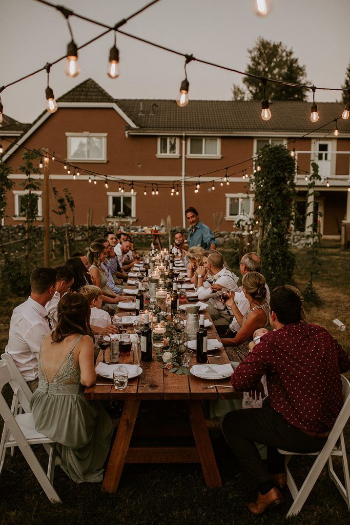 a group of people sitting around a table with food on it in front of a house