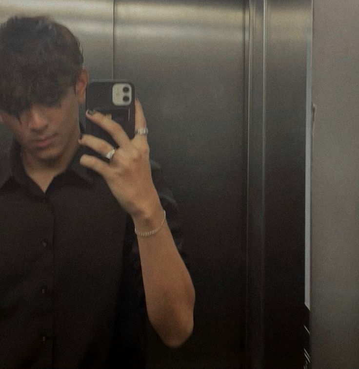 a man taking a selfie with his cell phone in front of an elevator door