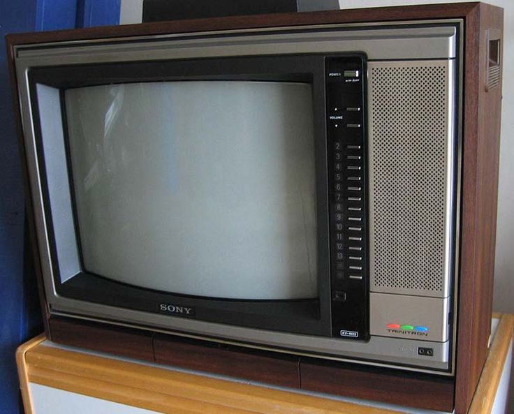 an old tv sitting on top of a wooden stand in front of a blue wall