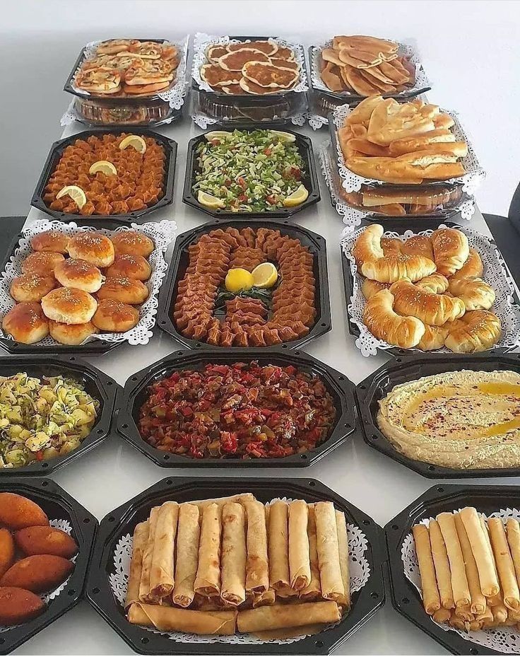 a table topped with lots of trays filled with different types of foods and pastries