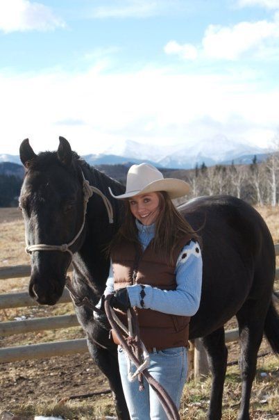 a woman standing next to a black horse