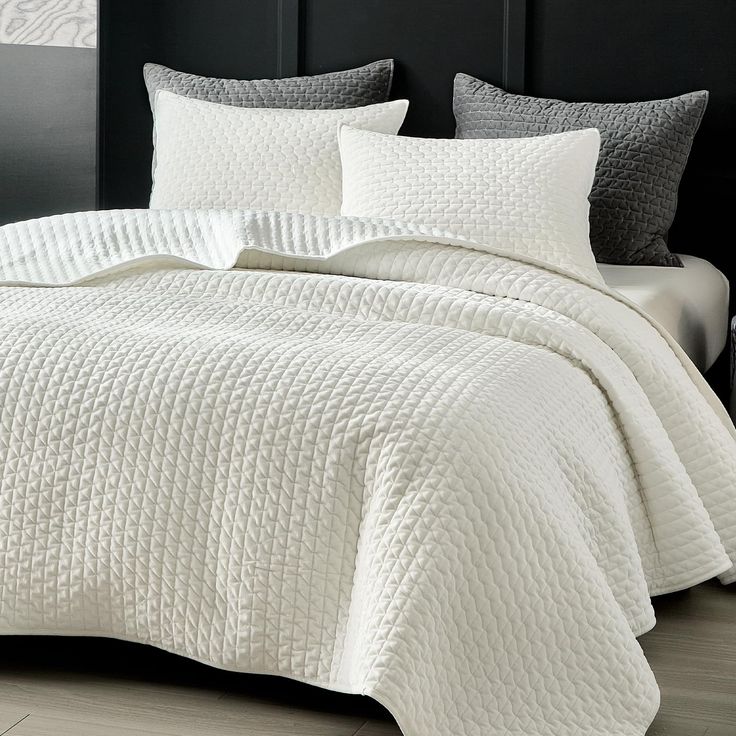 a white quilted bed with two pillows