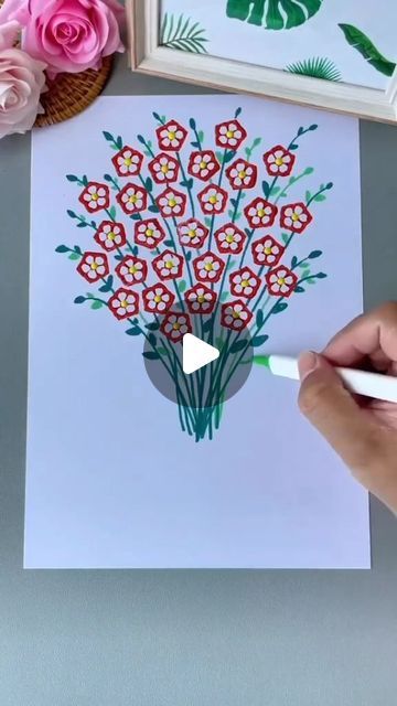 someone is drawing flowers on a piece of paper