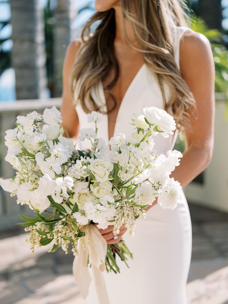 a woman holding a bouquet of white flowers