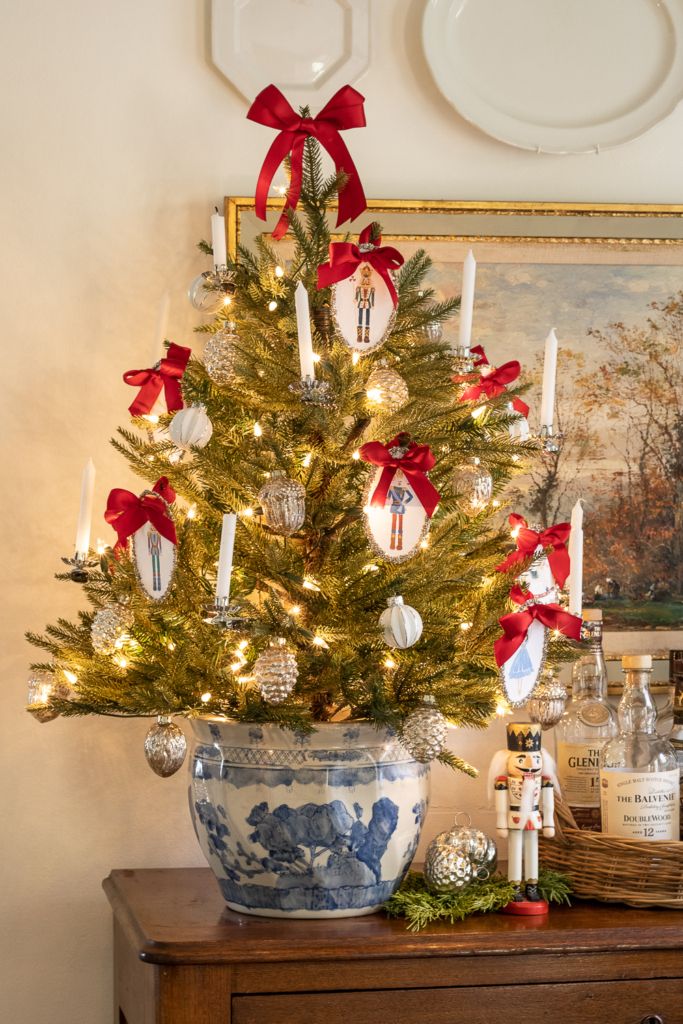 a decorated christmas tree in a blue and white china bowl with red bows on it