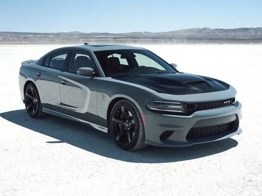 the dodge charger is parked in an empty desert area with mountains in the background