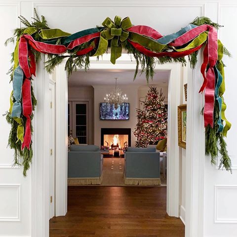 a living room decorated for christmas with red, green and blue ribbons hanging from the ceiling