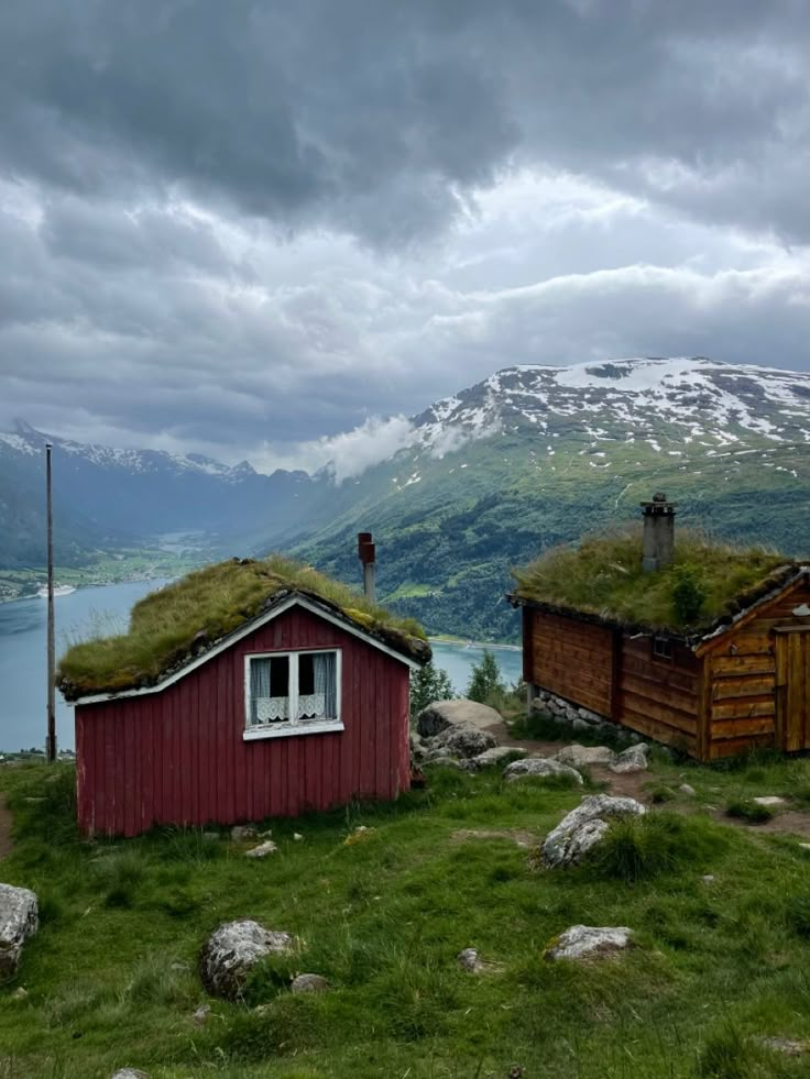 two small houses with grass roofs in the mountains