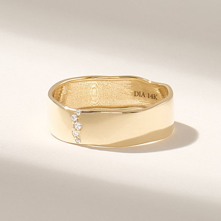 a close up of a gold ring on a white surface with a diamond in the middle