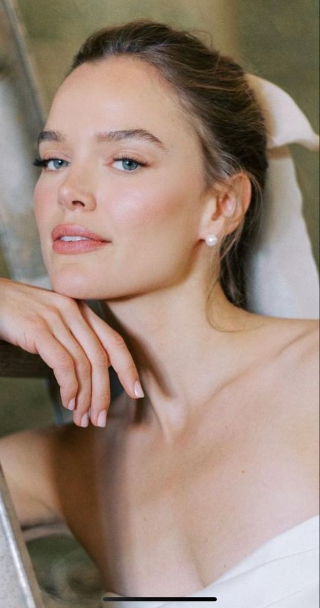 a woman in a white dress sitting on a chair with her hand on her shoulder