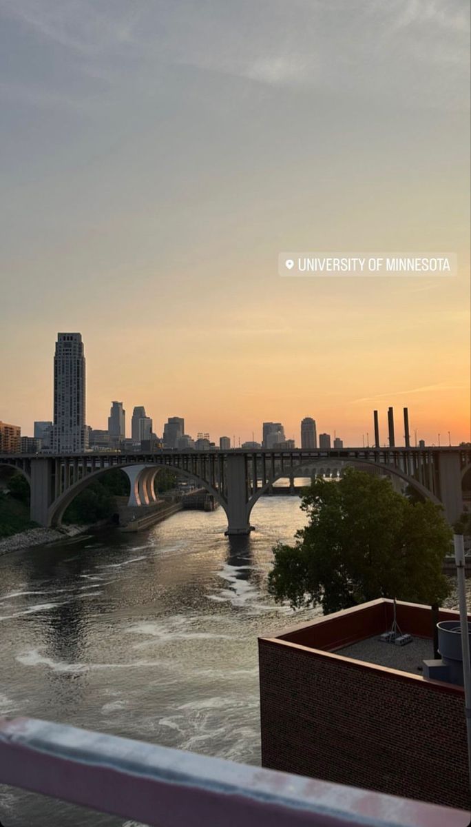 the sun is setting over a river with bridges and buildings in the backgroud