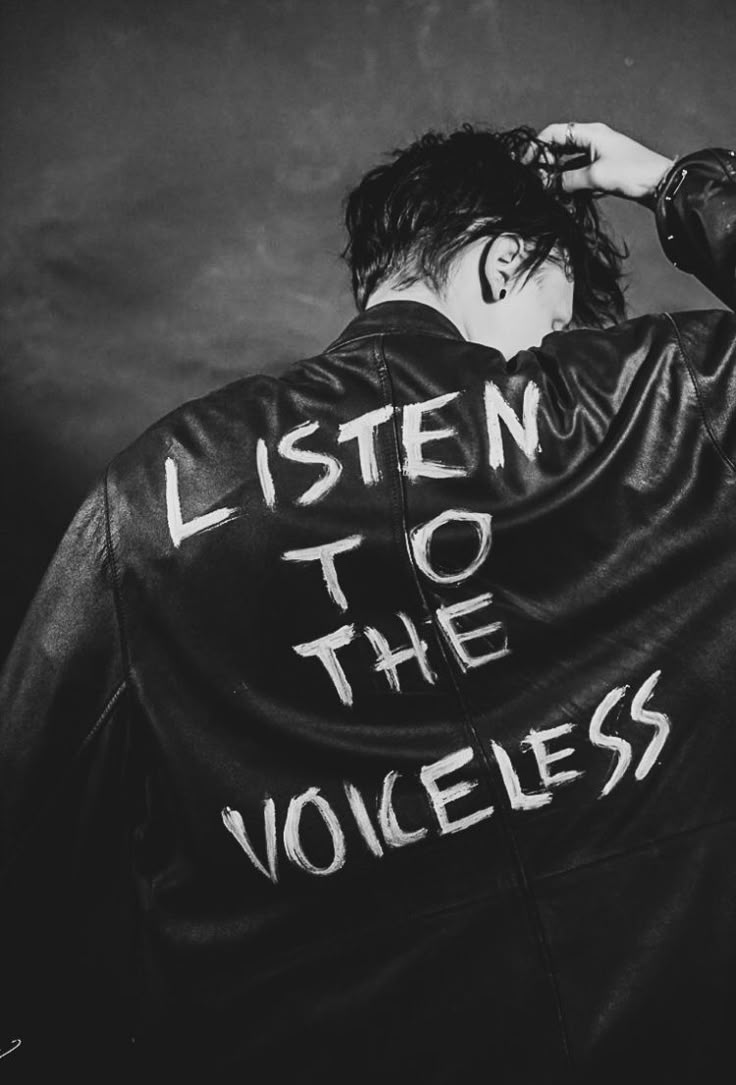 black and white photograph of a man wearing a leather jacket with the words listen to the voiceless written on it