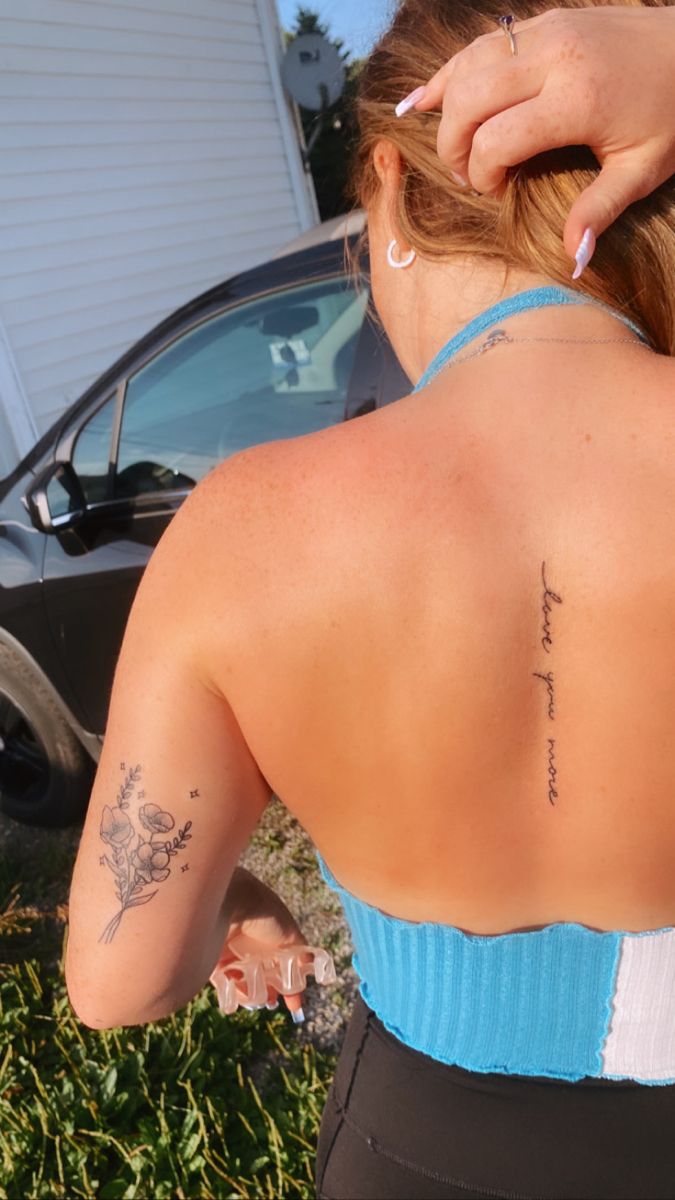 a woman with a tattoo on her back is standing in front of a parked car