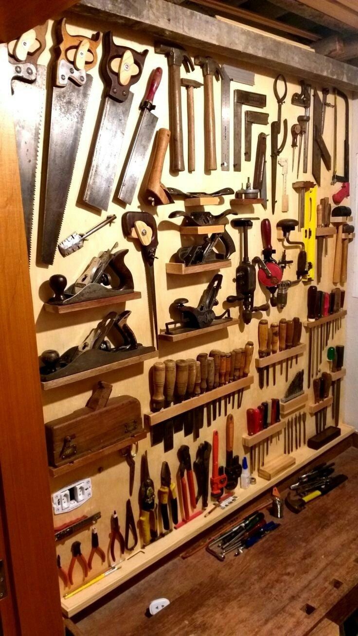 a workbench with lots of tools hanging on the wall