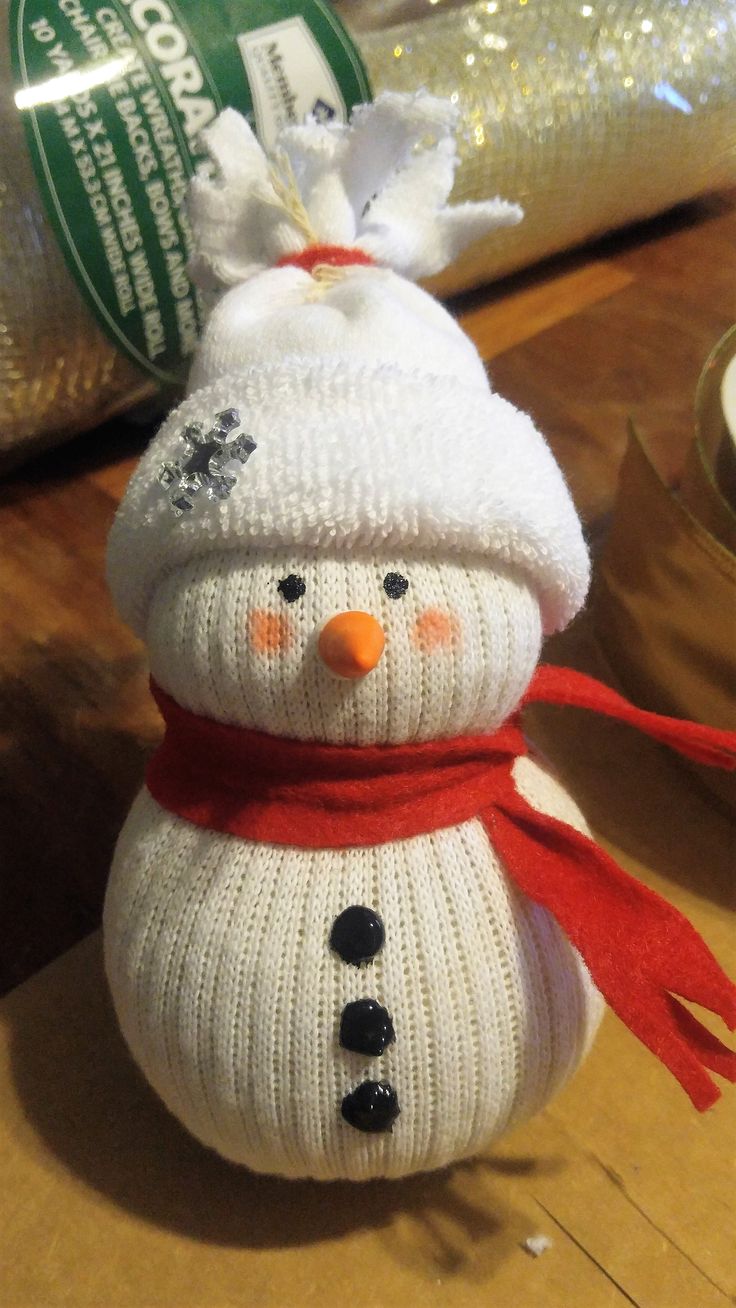 a knitted snowman sitting on top of a wooden table next to a bag