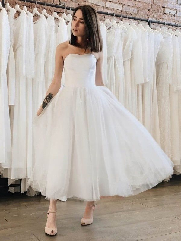 a woman wearing a white dress standing in front of some dresses