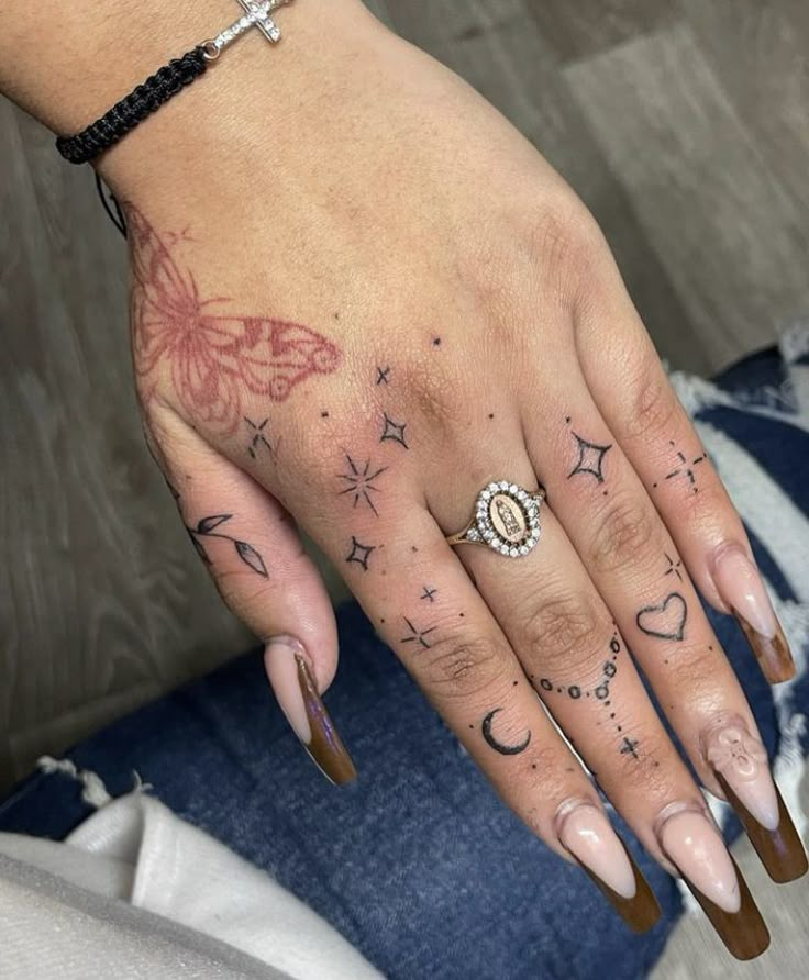 a woman's hand with tattoos on it and a cross tattooed on the ring finger