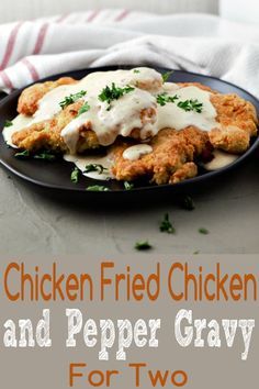 chicken fried chicken and pepper gravy for two on a black plate with parsley