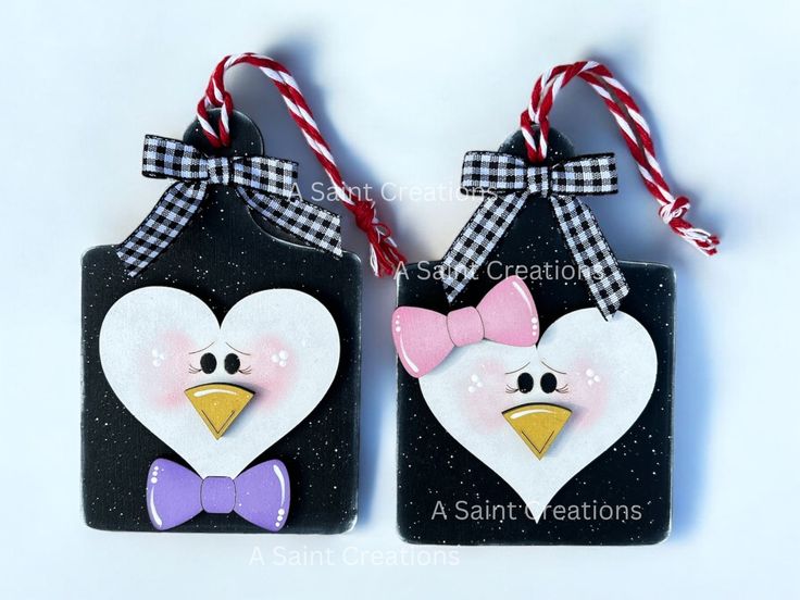 two black and white tags with pink bows on them, one is shaped like a penguin