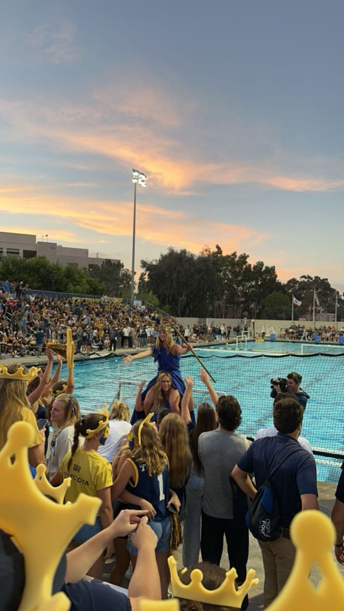 a group of people standing in front of a swimming pool with an audience watching them