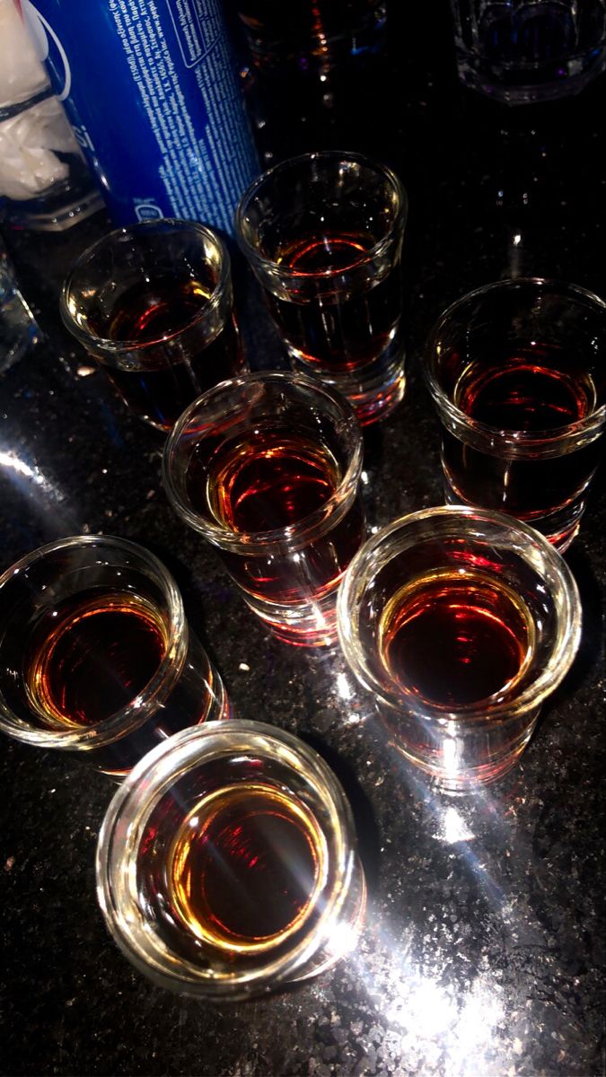 four glasses filled with liquid sitting on top of a table