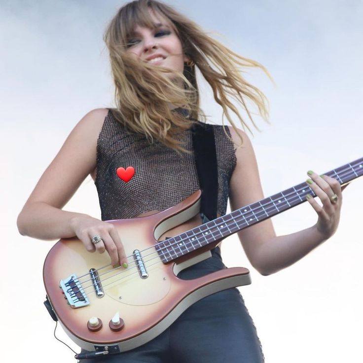 a woman holding a guitar and smiling at the camera