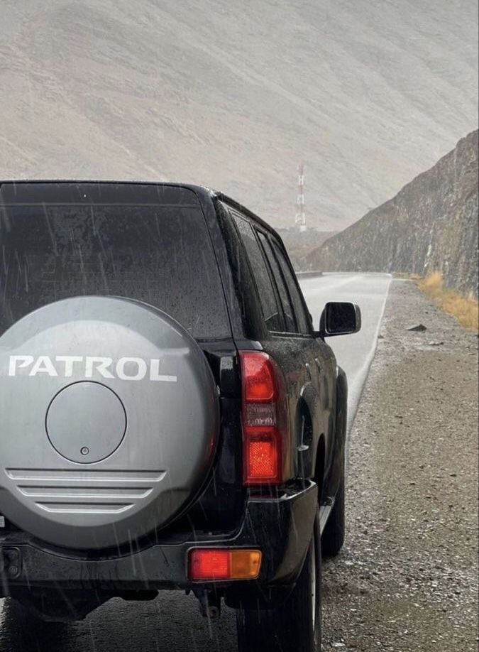 an suv parked on the side of a road with its tail lights turned off and rain falling