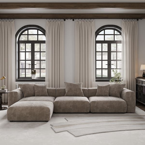 a living room with two large windows and a sectional couch