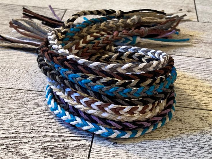 several braided bracelets sitting on top of a wooden floor