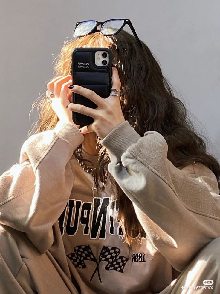 a woman taking a selfie with her cell phone in front of her face and wearing glasses