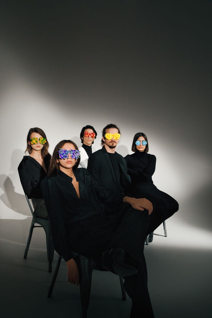 four people sitting in chairs with masks on their faces and one person standing behind them